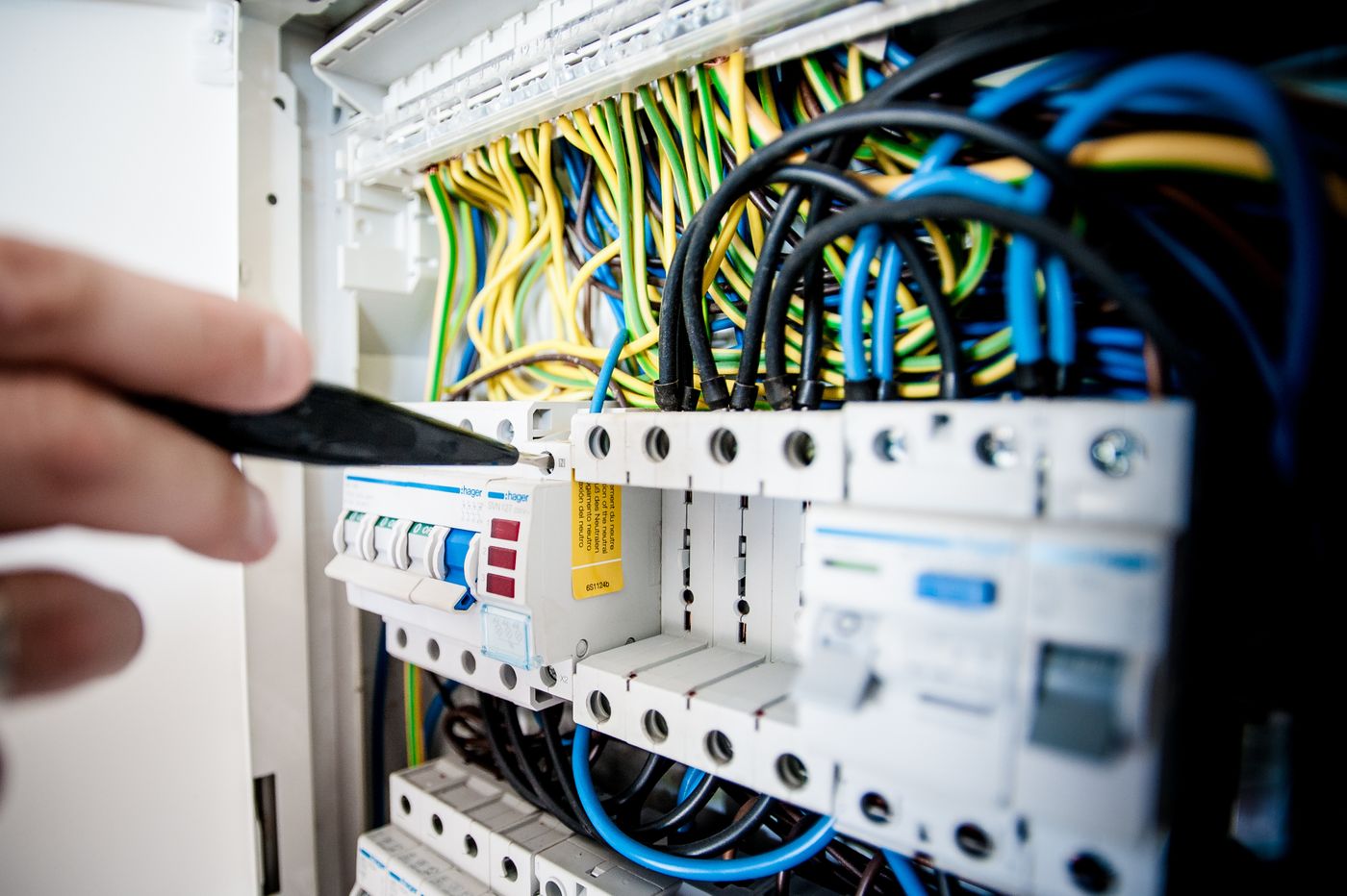 An electrician testing a consumer unit with a screwdriver